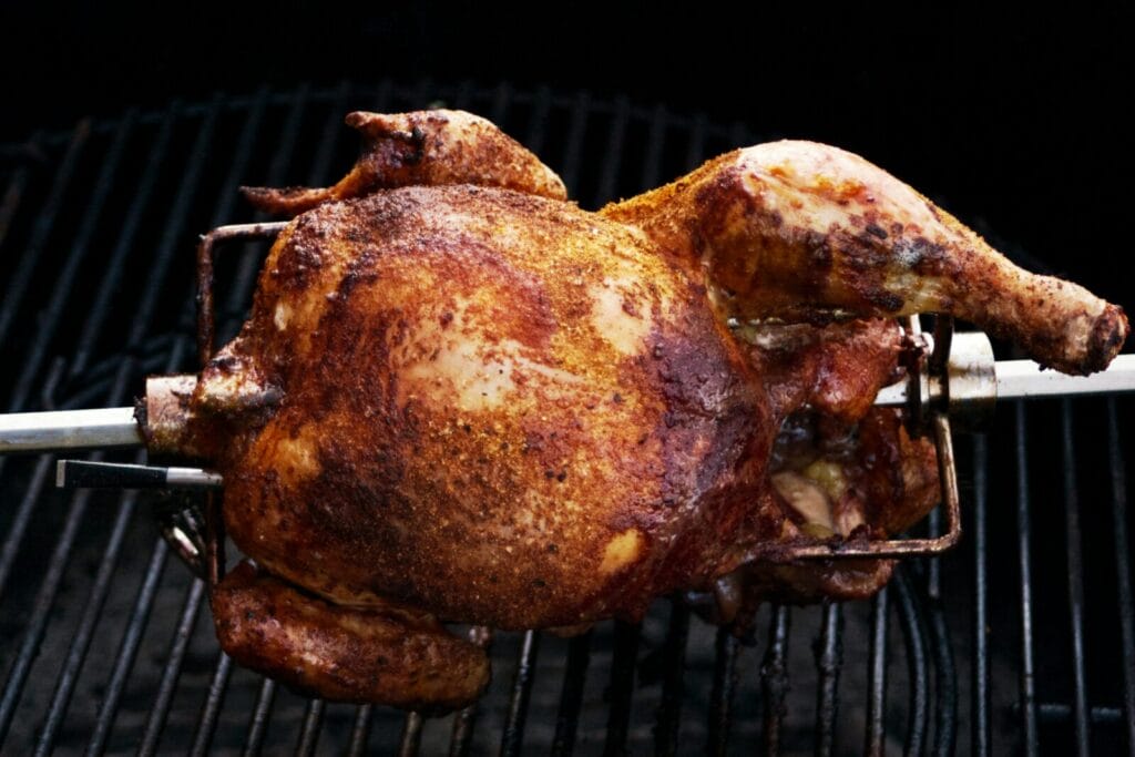 A rotisserie chicken on the spit being cooked. Photo by Sven Lippmann on Unsplash
