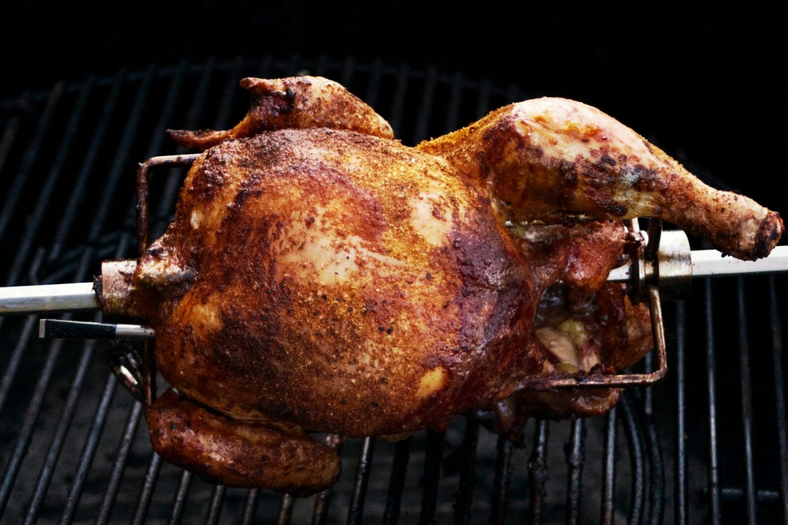 A rotisserie chicken on the spit being cooked. Photo by Sven Lippmann on Unsplash
